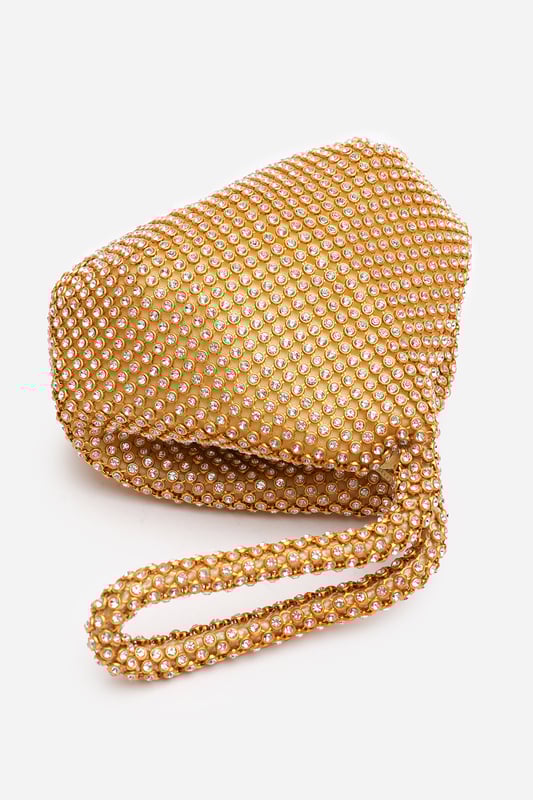 Add sparkle to your night with this Cascabel mini chainmail pouch bag, designed to dazzle at parties, weddings, or festive occasions. Its compact silhouette features shimmering crystal-style embellishments and a stylish knotted wristlet strap for easy carrying. Lightweight yet eye-catching, it's the perfect accessory for carrying your small essentials in glamorous style. A chic statement piece that blends retro charm with modern flair. Key Features: • Material: Rhinestone-embellished chainmail mesh • Dimensions: 16cm (L) x 14cm (H) x 10cm (W) • Fastening: Hidden zip closure at the top • Detail: Knotted wristlet strap for a secure and stylish hold