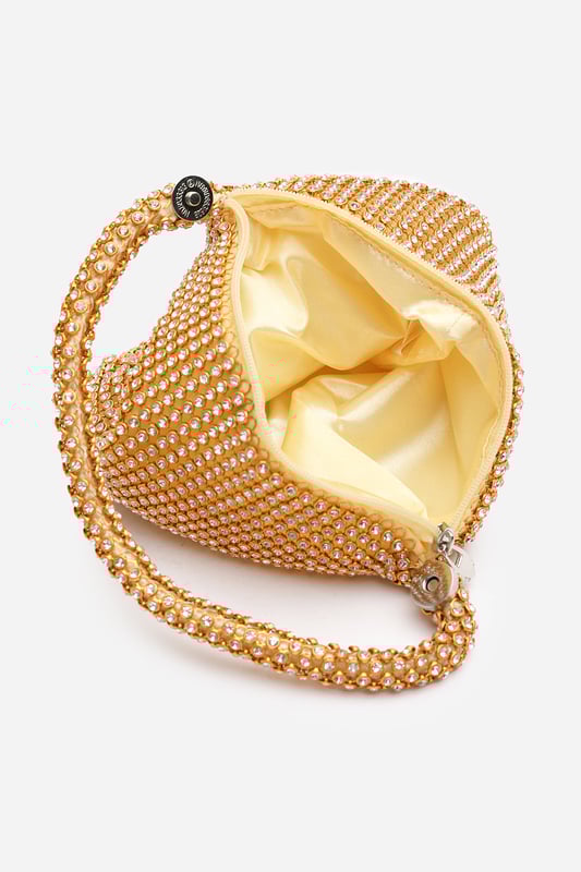 Add sparkle to your night with this Cascabel mini chainmail pouch bag, designed to dazzle at parties, weddings, or festive occasions. Its compact silhouette features shimmering crystal-style embellishments and a stylish knotted wristlet strap for easy carrying. Lightweight yet eye-catching, it's the perfect accessory for carrying your small essentials in glamorous style. A chic statement piece that blends retro charm with modern flair. Key Features: • Material: Rhinestone-embellished chainmail mesh • Dimensions: 16cm (L) x 14cm (H) x 10cm (W) • Fastening: Hidden zip closure at the top • Detail: Knotted wristlet strap for a secure and stylish hold