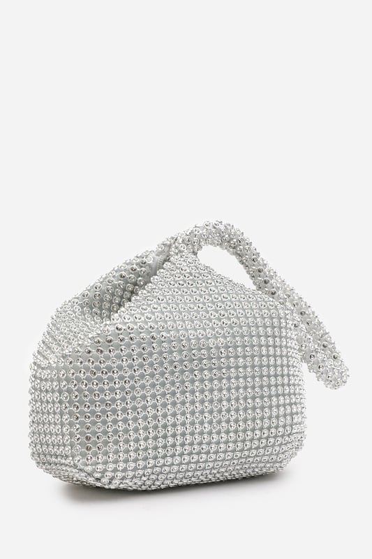 Add sparkle to your night with this Cascabel mini chainmail pouch bag, designed to dazzle at parties, weddings, or festive occasions. Its compact silhouette features shimmering crystal-style embellishments and a stylish knotted wristlet strap for easy carrying. Lightweight yet eye-catching, it's the perfect accessory for carrying your small essentials in glamorous style. A chic statement piece that blends retro charm with modern flair. Key Features: • Material: Rhinestone-embellished chainmail mesh • Dimensions: 16cm (L) x 14cm (H) x 10cm (W) • Fastening: Hidden zip closure at the top • Detail: Knotted wristlet strap for a secure and stylish hold