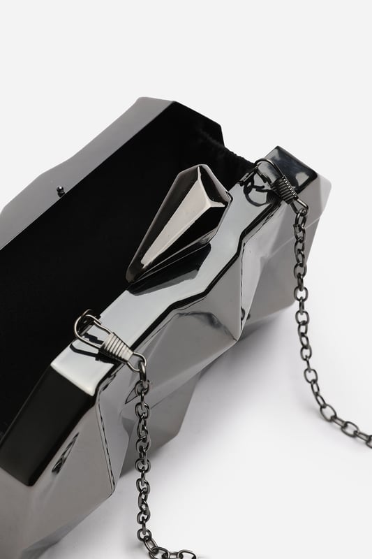 Turn heads with this striking Rica geometric clutch bag, designed to make a bold fashion statement at any evening event. The angular, high-gloss surface creates a modern 3D effect that reflects light from every angle. Its compact hard case keeps essentials secure while offering standout style. Perfect for weddings, parties, or night outs. Key Features: • Material: High-shine acrylic hard case with faceted geometric design • Dimensions: 18cm (L) x 9cm (H) x 6cm (W) • Fastening: Top snap clasp closure • Detail: Unique polygonal surface with a sculptural silhouette