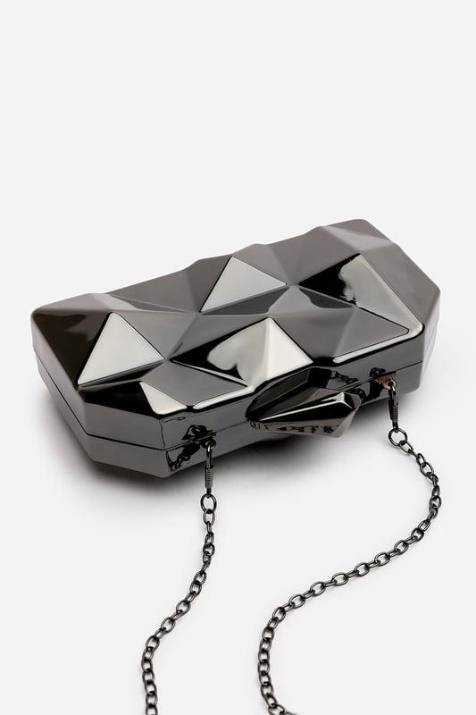 Turn heads with this striking Rica geometric clutch bag, designed to make a bold fashion statement at any evening event. The angular, high-gloss surface creates a modern 3D effect that reflects light from every angle. Its compact hard case keeps essentials secure while offering standout style. Perfect for weddings, parties, or night outs. Key Features: • Material: High-shine acrylic hard case with faceted geometric design • Dimensions: 18cm (L) x 9cm (H) x 6cm (W) • Fastening: Top snap clasp closure • Detail: Unique polygonal surface with a sculptural silhouette