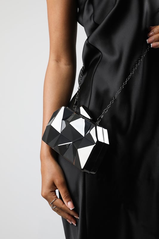 Turn heads with this striking Rica geometric clutch bag, designed to make a bold fashion statement at any evening event. The angular, high-gloss surface creates a modern 3D effect that reflects light from every angle. Its compact hard case keeps essentials secure while offering standout style. Perfect for weddings, parties, or night outs. Key Features: • Material: High-shine acrylic hard case with faceted geometric design • Dimensions: 18cm (L) x 9cm (H) x 6cm (W) • Fastening: Top snap clasp closure • Detail: Unique polygonal surface with a sculptural silhouette