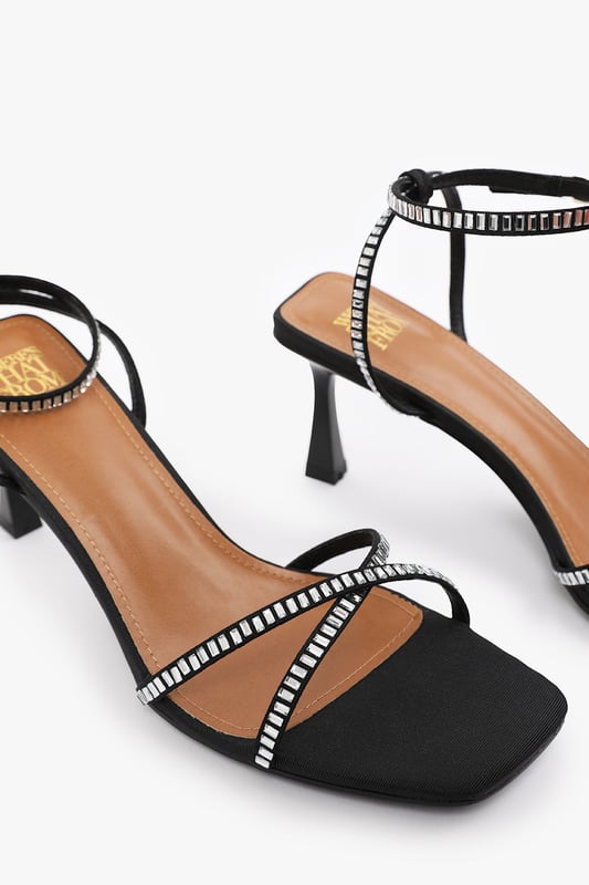 Introduce a touch of glamour to your footwear collection with our Sammi Square Toe Low Block Heel with Diamante Cross Over Strap Detail. These heels are the epitome of elegance and sophistication, making them the perfect finishing touch to any outfit, whether it's for a formal event, a night out, or a special occasion. Key Features: • Exquisite Design: The square toe silhouette of these high heels exudes a timeless appeal that never goes out of style. Enhanced by the diamante detail strap, these shoes are guaranteed to make heads turn. • High-Quality Construction: Crafted from premium materials, these high heels are designed to last. The high-quality construction ensures long-lasting durability while maintaining the comfort of your feet. • Versatile Addition: These are more than just your regular high heels. Make an entrance at any event. Be it a lavish wedding, a formal workplace event, or a casual outing with friends. The classy square-toe design with the decorative diamante detail is versatile enough to pair with a variety of outfits and are your perfect partner for a chic update to your look. Specifications: • Closure: Ankle strap with buckle. • Heel Height: 3.3' (8.3cm) approx Invest in our Sammi Square Toe Low Block Heel with Diamante Cross Over Strap Detail and bring that extra touch of elegance and sophistication to your wardrobe. They speak loud and clear of luxury and style – a piece worth showcasing!