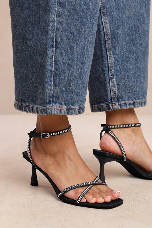 Introduce a touch of glamour to your footwear collection with our Sammi Square Toe Low Block Heel with Diamante Cross Over Strap Detail. These heels are the epitome of elegance and sophistication, making them the perfect finishing touch to any outfit, whether it's for a formal event, a night out, or a special occasion. Key Features: • Exquisite Design: The square toe silhouette of these high heels exudes a timeless appeal that never goes out of style. Enhanced by the diamante detail strap, these shoes are guaranteed to make heads turn. • High-Quality Construction: Crafted from premium materials, these high heels are designed to last. The high-quality construction ensures long-lasting durability while maintaining the comfort of your feet. • Versatile Addition: These are more than just your regular high heels. Make an entrance at any event. Be it a lavish wedding, a formal workplace event, or a casual outing with friends. The classy square-toe design with the decorative diamante detail is versatile enough to pair with a variety of outfits and are your perfect partner for a chic update to your look. Specifications: • Closure: Ankle strap with buckle. • Heel Height: 3.3' (8.3cm) approx Invest in our Sammi Square Toe Low Block Heel with Diamante Cross Over Strap Detail and bring that extra touch of elegance and sophistication to your wardrobe. They speak loud and clear of luxury and style – a piece worth showcasing!