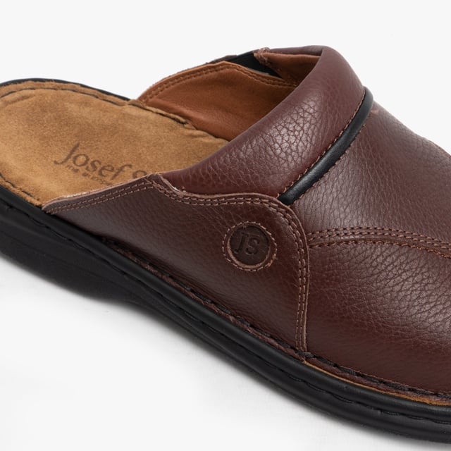 Esta mule de cuero para hombres cuenta con un forro textil transpirable, suela de poliuretano y un diseño sin cierre con punta redonda, ofreciendo comodidad y un tacón plano para un uso casual.
