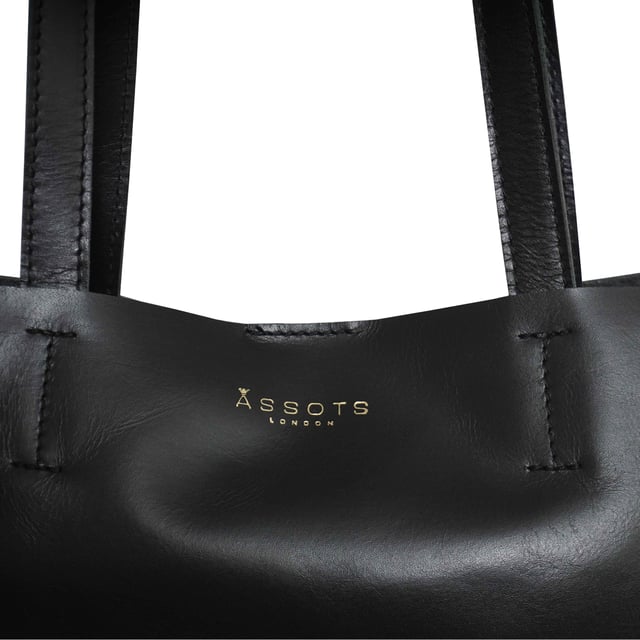 The 'Adela' genuine leather tote bag is beautifully handcrafted from premium Italian finish semi-soft and supple leather. Chosen for its durability, this timeless piece adds a touch of sophistication to all your outfits. Ideal for travel, meetings and everyday use, this chic handbag is a must-have addition to your collection of designer bags. Unlined for a robust and hard-wearing central compartment with an exposed, soft to the touch natural leather interior. Magnetic fastening closure opens to a roomy and spacious interior. Reinforced handle stitching to avoid snapping due to the load in the bag. Soft leather shoulder handles for a comfortable carry. Adorned with the inimitable Assots London clean finish gold embossed logo. Fittings colour: Shiny Gold. Composition: Body: 100% Genuine Leather. Lining: Unlined. DISCLAIMER : All pictures shown are for illustration purpose only. Actual product colour may vary due to different ambience lighting or the screen display settings.