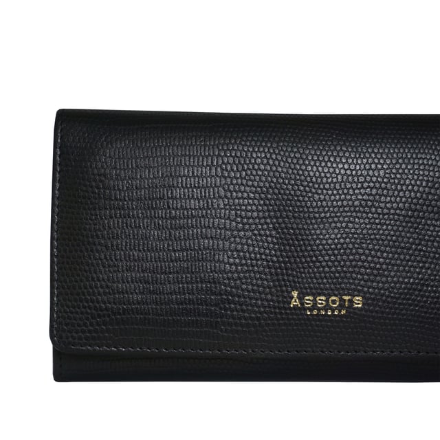 The ‘Claire’ flapover ladies purse is handcrafted with the premium lizard textured leather to give that designer look. Equipped with RFID technology, this practical ladies purse features a magnetic fastening closure with plenty of room to organise your cash, cards and coins. This large leather ladies purse is perfect to compliment your handbag and fits in easily. Stay safe and organised with ‘Claire’ the perfect addition to your collection of purses ideal for all outfits and occasions. Secured flap over magnetic fastening closure to store your essentials safely and securely. Foldover flap design. Equipped with RFID technology for safety. Additional back zip pocket to ensure you don’t run out of space. Two note compartments. Eight internal card compartments. Two windowed ID slots. Assots branded lined interiors. Lightweight for easy carry. Fittings Colour: Clean Brass. Composition: Body: 100% Genuine Leather. Lining: 100% Cotton. DISCLAIMER : All pictures shown are for illustration purpose only. Actual product colour may vary due to different ambience lighting or the screen display settings.