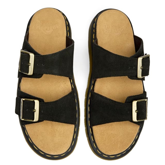 The Dr Martens Josef brings the brand's rebellious DNA to warm-weather footwear with bold confidence. Crafted from rich black suede, these slides feature the iconic twin buckle design that's both functional and unmistakably DM. The signature AirWair sole delivers the comfort and durability you expect, while side-stitched construction ensures these sandals can handle whatever your summer throws at them.