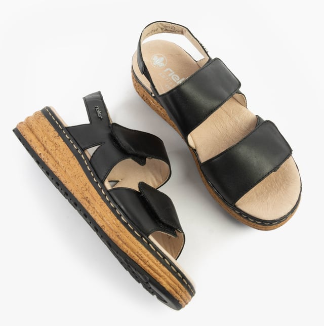 These open-toe women's sandals feature a leather upper, breathable lining, wedge heel, and extra-wide fit for comfort. Ideal for casual wear and easy to slip on with touch fasten closure
