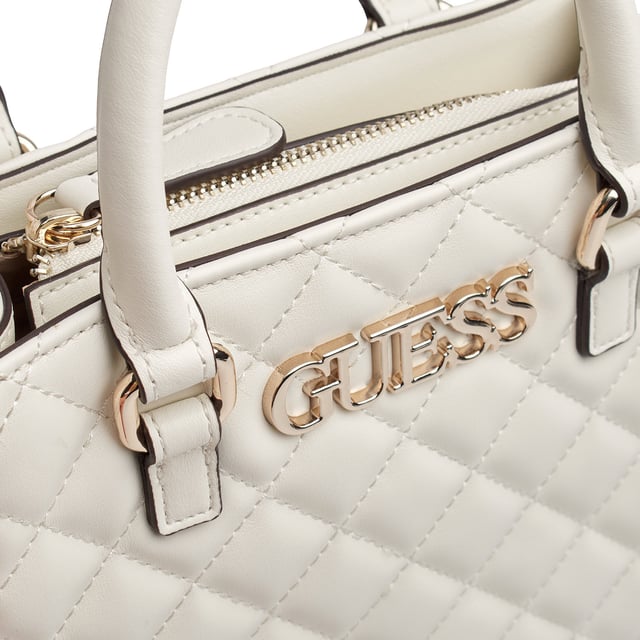 Este bolso tote pequeño de Guess destaca por su diseño acolchado con patrón de rombos y un aire sofisticado que eleva cualquier look. Compacto pero con espacio suficiente para lo esencial, incluye asas estructuradas y una correa con eslabones metálicos para mayor versatilidad. Su silueta refinada lo convierte en el accesorio ideal para acompañarte con estilo en el día a día.\n\nDetalles:\n- Tipo de accesorio: Bolso tote pequeño.\n- Material: Material sintético tipo piel.\n- Textura: Acolchada con diseño de rombos.\n- Herraje: Metálico en tono dorado.\n- Detalles exteriores: Logo metálico Guess en la parte frontal.\n- Detalles interiores: Compartimento principal con cremallera,1 bolsillo trasero con cremallera, 2 bolsillos frontales abiertos.\n- Asas de mano estructuradas.\n- Correa ajustable y extraíble con cadena metálica decorativa.\n\nGuess apuesta por un diseño compacto y elegante que fusiona comodidad y estilo. Este bolso tote pequeño es perfecto para quienes buscan una pieza funcional con personalidad, ideal tanto para el día como para salidas más especiales.\n Medidas: 21.5 x 20.5 x 7 cm\n Composición: 100% Poliuretano\n Cuidados:\nLimpiar con un paño suave y ligeramente húmedo.\nNo usar productos abrasivos ni detergentes.\nEvitar la exposición prolongada al sol o humedad extrema.