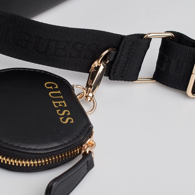 Deze schoudertas van Guess maakt indruk met zijn compacte en functionele ontwerp - perfect om elke dag te dragen. Hij is gemaakt van kunstleer en heeft metallic details en afneembare accessoires die de urban stijl benadrukken. Dankzij het praktische ontwerp met ruime binnen- en buitenvakken is hij ideaal om alles binnen handbereik te houden. De verstelbare riem zorgt voor een veelzijdige pasvorm, zowel over de schouder als over het lichaam.\n\n - Type accessoire: Schoudertas.\n - Materiaal: Synthetisch, leerachtig materiaal.\n - Textuur: Glad.\n - Hardware: Goudkleurig metaal.\n - Details buitenkant: Voorvak met metalen Guess-plaatje.\n - Verdere details: Rond muntzakje met ritssluiting en afneembare kaarthouder.\n - Details interieur: Hoofdvak met ritssluiting, 3 open vakken, 1 ritsvak, 2 kaartsleuven.\n - Verstelbare brede riem.\n\n In elk ontwerp combineert Guess zijn kenmerkende essentie met een moderne, onmiskenbare stijl. Deze damesschoudertas weerspiegelt de stedelijke en functionele stijl van het merk: een perfecte mix van mode en functionaliteit, ideaal om je te vergezellen op al je reizen met een opvallende touch.\n Afmetingen: Tas: 21,5 x 14 x 7 cm; Platte tas: 11 x 8 cm; Ronde tas: 8,7 x 8 x 2 cm\n Samenstelling: 100% polyurethaan\n Onderhoud:\nSchoonmaken met een zachte, licht vochtige doek.\n Gebruik geen schurende schoonmaakmiddelen of detergenten.\n Vermijd langdurige blootstelling aan zonlicht of extreme vochtigheid.