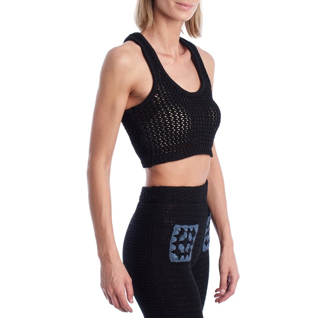 Este top corto confeccionado en punto calado combina estilo artesanal con una silueta deportiva. El diseño de escote redondo y espalda nadadora aporta un aire moderno y fresco, ideal para combinar con pantalones o faldas de punto para un conjunto coordinado. Su tejido abierto permite una mayor transpirabilidad y añade un efecto visual sugerente y veraniego.\n\nDetalles:\n- Corte: Cropped con ajuste ceñido.\n- Exterior: Tejido de punto calado artesanal.\n- Espalda: Diseño nadadora para un look deportivo.\n- Estilo: Casual y bohemio, ideal para verano.\n- Funcionalidad: Perfecto para llevar sobre bikini o como top de conjunto.\n\nCrea un conjunto llamativo combinándolo con su pantalón a juego, y eleva tus looks de verano con un toque boho-chic.\n Composición: 100% Algodón\n Cuidados:\nLavar a mano en agua fría. No usar secadora. Secar en plano.