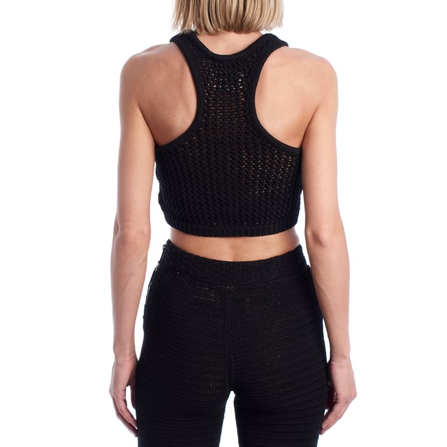 Este top corto confeccionado en punto calado combina estilo artesanal con una silueta deportiva. El diseño de escote redondo y espalda nadadora aporta un aire moderno y fresco, ideal para combinar con pantalones o faldas de punto para un conjunto coordinado. Su tejido abierto permite una mayor transpirabilidad y añade un efecto visual sugerente y veraniego.\n\nDetalles:\n- Corte: Cropped con ajuste ceñido.\n- Exterior: Tejido de punto calado artesanal.\n- Espalda: Diseño nadadora para un look deportivo.\n- Estilo: Casual y bohemio, ideal para verano.\n- Funcionalidad: Perfecto para llevar sobre bikini o como top de conjunto.\n\nCrea un conjunto llamativo combinándolo con su pantalón a juego, y eleva tus looks de verano con un toque boho-chic.\n Composición: 100% Algodón\n Cuidados:\nLavar a mano en agua fría. No usar secadora. Secar en plano.
