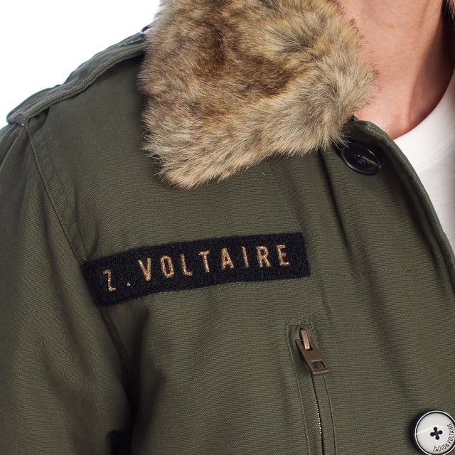 Parka larga de Zadig & Voltaire con diseño funcional y espíritu utilitario. Presenta un corte recto con largo por encima de la rodilla y cierre de botones frontales. El cuello está rematado con un forro de pelo sintético extraíble que añade calidez y contraste de texturas. Incluye bolsillos amplios con solapa, cremallera y botón, así como detalles bordados y una etiqueta bordada con el nombre de la firma.\n\nDetalles:\n- Corte: Recto, largo medio.\n- Exterior: Parka con cierre de botones, bolsillos múltiples y bordado de inspiración militar.\n- Interior: Forro acolchado de costura ondulada para mayor aislamiento.\n- Cuello: Pelo sintético desmontable para adaptar la prenda a diferentes temperaturas.\n- Funcionalidad: Diseño robusto y práctico con estética contemporánea.\n\nPerfecta para quienes buscan una chaqueta cálida con carácter, ideal para looks casuales con personalidad.\n Composición: Exterior: 100% Algodón; Interior: 100% Poliéster\n Cuidados:\nLimpieza en seco recomendada para preservar la estructura y los detalles del tejido.\nNo usar lejía ni blanqueadores.\n\nNo utilizar secadora.\n\nPlanchar a temperatura baja si es necesario, evitando el área del pelo sintético.