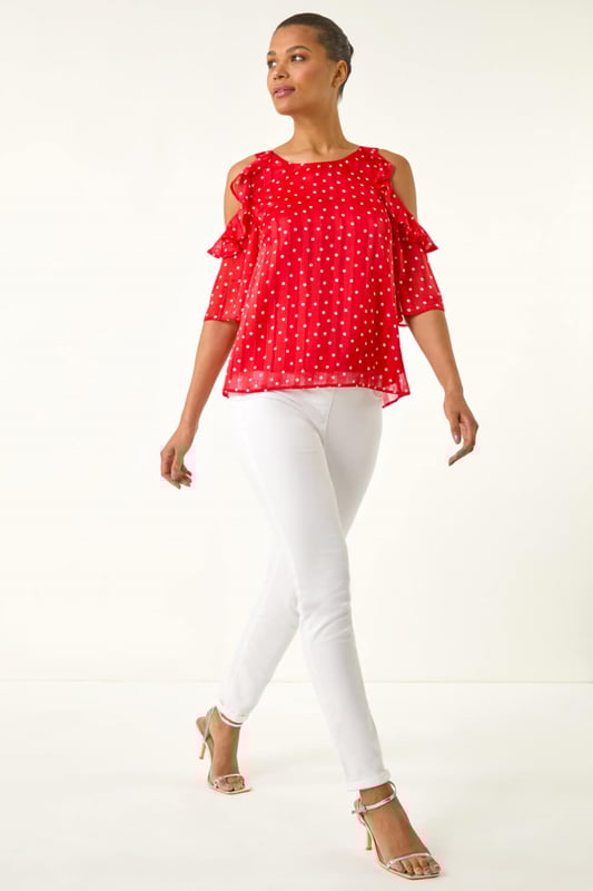 Spot Print Frill Cold Shoulder Top from Roman. Get ready to make a statement this Spring Summer with this spot print cold shoulder top. The trendy round neckline and frill shoulder detail add a fun and flirty touch to this piece, crafted from a comfortable satin woven fabric. Perfect for sunny days, pair this top with linen trousers and sandals for a sophisticated and stylish look!
