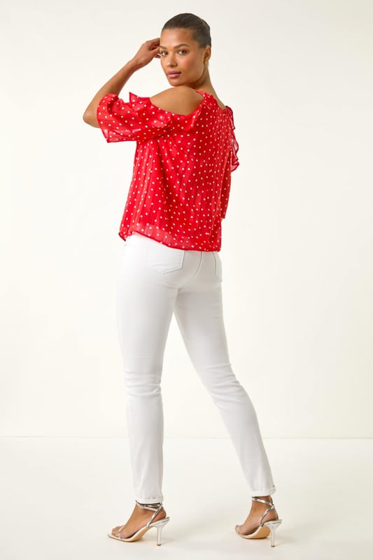 Spot Print Frill Cold Shoulder Top from Roman. Get ready to make a statement this Spring Summer with this spot print cold shoulder top. The trendy round neckline and frill shoulder detail add a fun and flirty touch to this piece, crafted from a comfortable satin woven fabric. Perfect for sunny days, pair this top with linen trousers and sandals for a sophisticated and stylish look!