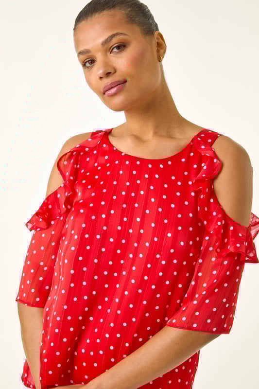 Spot Print Frill Cold Shoulder Top from Roman. Get ready to make a statement this Spring Summer with this spot print cold shoulder top. The trendy round neckline and frill shoulder detail add a fun and flirty touch to this piece, crafted from a comfortable satin woven fabric. Perfect for sunny days, pair this top with linen trousers and sandals for a sophisticated and stylish look!