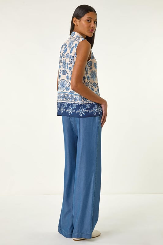 Border Print Collared Blouse Border Print Collared Blouse from Roman. Add a touch of elegance to your Spring/Summer wardrobe with this sleeveless all over print blouse. Featuring a chic border detail at the hem and collar, this blouse opens fully via buttons for easy wear. Perfect for any occasion, pair with tailored trousers and heels for a sophisticated look!
