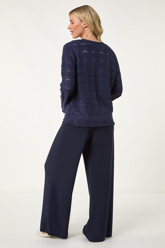 Petite Knitted Tie Cardigan from Roman. Elevate your knitwear collection with this charming v-neck cardigan. Crafted from a knitted fabric, this edge to edge cardigan features a unique tie fastening at the bust for added detail. The scallop style hem and pointelle detail along with the long sleeves make this cardigan a standout piece. Pair with jeans and sandals for a laid-back and stylish look this Spring/Summer season!