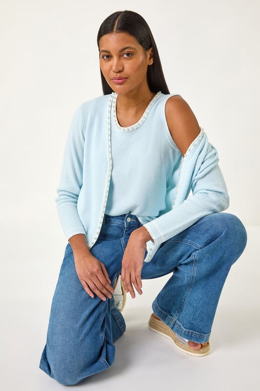 Faux Pearl Trim Cardigan from Roman. Add a touch of elegance to any outfit with this chic faux pearly detail cardigan. The perfect Spring/Summer cover-up, featuring long sleeves and an edge to edge front for effortless style. Layer over a floral dress and heels for a classic and sophisticated look.