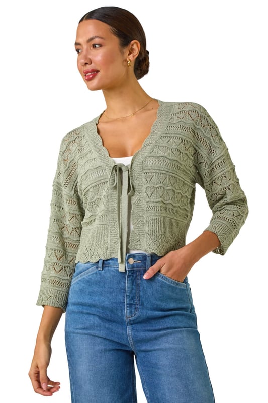 Textured Scallop Shrug from Roman. Add a touch of elegance to your outfit with this stunning scallop shrug, perfect for the Spring/Summer season. Crafted from textured tape yarn, this shrug features chic 3/4 sleeves and a soft hand touch for ultimate comfort. The scallop detailing adds a fun and stylish twist to the classic shrug style. Pair it with a simple t-shirt and jeans for a casual yet sophisticated look that can take you from day to night effortlessly.
