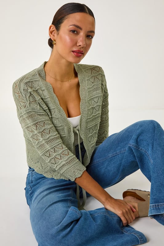 Textured Scallop Shrug from Roman. Add a touch of elegance to your outfit with this stunning scallop shrug, perfect for the Spring/Summer season. Crafted from textured tape yarn, this shrug features chic 3/4 sleeves and a soft hand touch for ultimate comfort. The scallop detailing adds a fun and stylish twist to the classic shrug style. Pair it with a simple t-shirt and jeans for a casual yet sophisticated look that can take you from day to night effortlessly.