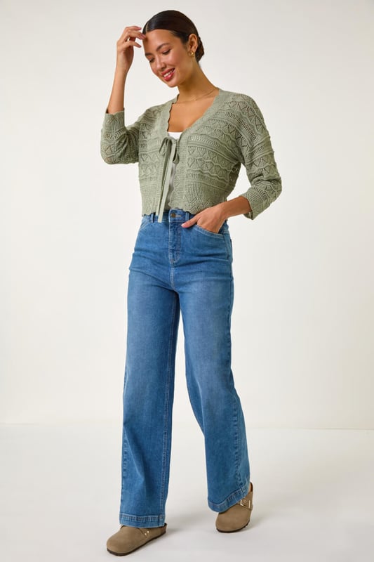 Textured Scallop Shrug from Roman. Add a touch of elegance to your outfit with this stunning scallop shrug, perfect for the Spring/Summer season. Crafted from textured tape yarn, this shrug features chic 3/4 sleeves and a soft hand touch for ultimate comfort. The scallop detailing adds a fun and stylish twist to the classic shrug style. Pair it with a simple t-shirt and jeans for a casual yet sophisticated look that can take you from day to night effortlessly.