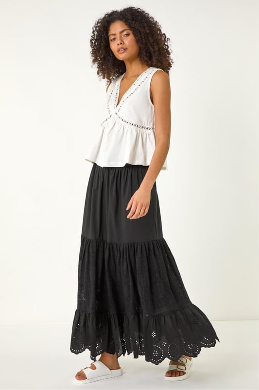 Dusk Tiered Broderie Maxi Skirt from Roman. Embrace summer vibes with this delightful tiered broderie skirt. The intricate broderie design adds a charming touch to this maxi length skirt, perfect for sunny days. The tierred style adds flow and movement to your look, creating an effortlessly feminine silhouette. Pair it with a simple cami top and sandals for an easy-breezy summer outfit that will keep you cool and stylish all day long.