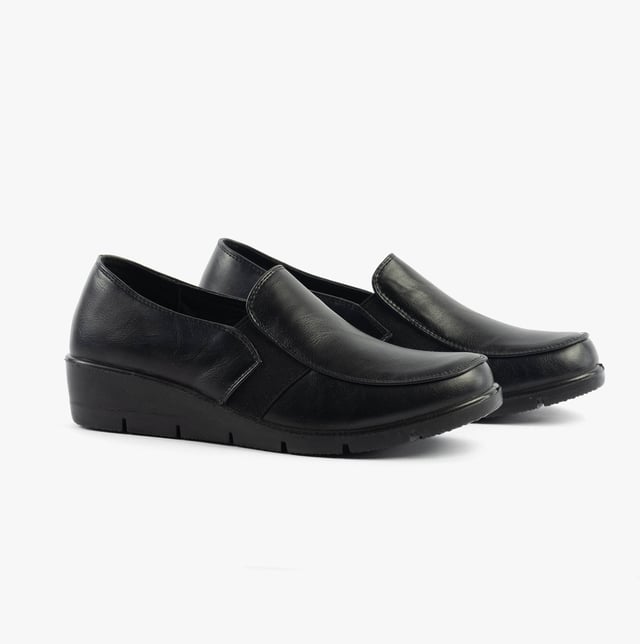 These casual women's slip-on shoes feature a leather upper, textile lining, rubber sole, and a low wedge heel, offering comfort and a wide fit for everyday wear