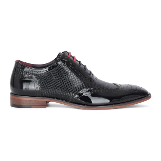 Realza tu look formal con los zapatos brogue Justin Reess Flynn de charol negro. Diseñados para una elegancia excepcional, estos zapatos presentan una parte superior de charol negro brillante con un sutil patrón texturizado, perfectos para bodas, eventos de gala o veladas sofisticadas. Los detalles brogue clásicos añaden un encanto tradicional, mientras que el diseño con cordones garantiza un ajuste seguro y a medida. Un suave forro interior aumenta la comodidad, haciéndolos ideales para un uso prolongado con confianza y estilo. Charol negro brillante con un sutil acabado texturizado para un look audaz y refinado. Brogue clásico. Perforaciones y costuras para una elegancia atemporal. Cierre seguro con cordones para un ajuste cómodo y ajustable. Interior con forro suave que aumenta la comodidad para usar todo el día. Silueta elegante perfecta para eventos formales, fiestas y ocasiones especiales. Confeccionados 100 % en cuero para mayor calidad y durabilidad.