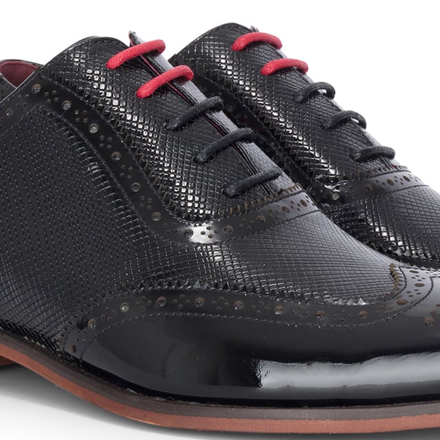 Realza tu look formal con los zapatos brogue Justin Reess Flynn de charol negro. Diseñados para una elegancia excepcional, estos zapatos presentan una parte superior de charol negro brillante con un sutil patrón texturizado, perfectos para bodas, eventos de gala o veladas sofisticadas. Los detalles brogue clásicos añaden un encanto tradicional, mientras que el diseño con cordones garantiza un ajuste seguro y a medida. Un suave forro interior aumenta la comodidad, haciéndolos ideales para un uso prolongado con confianza y estilo. Charol negro brillante con un sutil acabado texturizado para un look audaz y refinado. Brogue clásico. Perforaciones y costuras para una elegancia atemporal. Cierre seguro con cordones para un ajuste cómodo y ajustable. Interior con forro suave que aumenta la comodidad para usar todo el día. Silueta elegante perfecta para eventos formales, fiestas y ocasiones especiales. Confeccionados 100 % en cuero para mayor calidad y durabilidad.