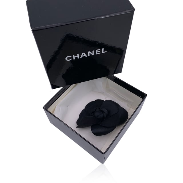 VINTAGE, RRP AS NEW
Elegant and unmistakably classic, this vintage Chanel Camellia brooch captures the essence of the house's refined femininity. The Camellia - a symbol of Chanel's enduring muse - blooms here in soft black silk, its petals gently layered to evoke quiet sophistication and grace.  With a generous diameter of 3.5 inches (8.9 cm), this statement piece is secured with a traditional safety pin closure. The reverse bears the iconic 'CHANEL - CC - Made in France' oval tab, marking its ity and Parisian heritage. A quintessential vintage treasure, perfect for adorning lapels, scarves, or bags with timeless allure. Condition Rating: A - EXCELLENTCondition Details: Gently used. Chanel box included. Please check the photos carefully and ask if you need to know more details or if you have any doubts.  Box?: ?: Yes