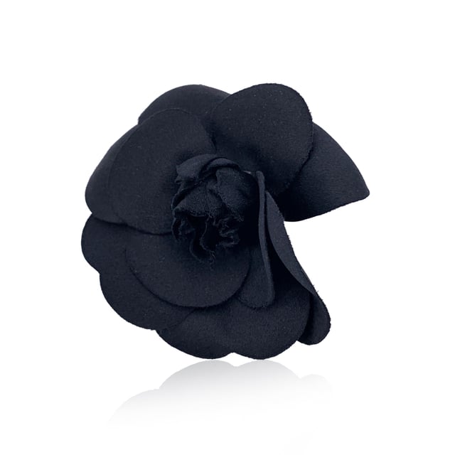 VINTAGE, RRP AS NEW
Elegant and unmistakably classic, this vintage Chanel Camellia brooch captures the essence of the house's refined femininity. The Camellia - a symbol of Chanel's enduring muse - blooms here in soft black silk, its petals gently layered to evoke quiet sophistication and grace.  With a generous diameter of 3.5 inches (8.9 cm), this statement piece is secured with a traditional safety pin closure. The reverse bears the iconic 'CHANEL - CC - Made in France' oval tab, marking its ity and Parisian heritage. A quintessential vintage treasure, perfect for adorning lapels, scarves, or bags with timeless allure. Condition Rating: A - EXCELLENTCondition Details: Gently used. Chanel box included. Please check the photos carefully and ask if you need to know more details or if you have any doubts.  Box?: ?: Yes