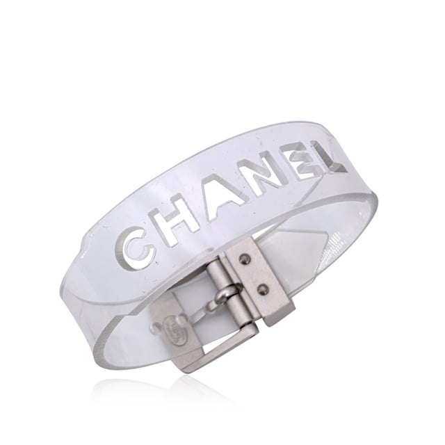 VINTAGE, RRP AS NEW
Add a playful twist of luxury to your collection with this lovely CHANEL bracelet, a rare and striking piece that fuses bold branding with unexpected materials. Crafted in clear transparent rubber, it's a standout example of late '90s CHANEL design-where classic elegance met avant-garde edge.  The bracelet features cut-out CHANEL lettering that runs boldly across its surface, allowing light to pass through for a modern, sculptural look. A buckle closure adds an industrial-chic touch, keeping the fit secure and adjustable.  Stamped with the 'Chanel 99 CC S Made in France' hallmark near the closure, this piece dates to 1999, offering collectors a glimpse into one of the brand's more experimental eras. At 8.25 inches (21 cm) in total length, it's designed to fit comfortably on most wrists.  Whether worn solo as a statement or layered with fine bangles for contrast, this bracelet is a perfect blend of vintage charm and futuristic flair-unmistakably CHANEL, and effortlessly cool. Condition Rating: A - EXCELLENTCondition Details: Minimal wear of use on rubber. Please, look carefully at the photos and ask for any detail.  Box?: ?: No Measurments:  length: 210 mm