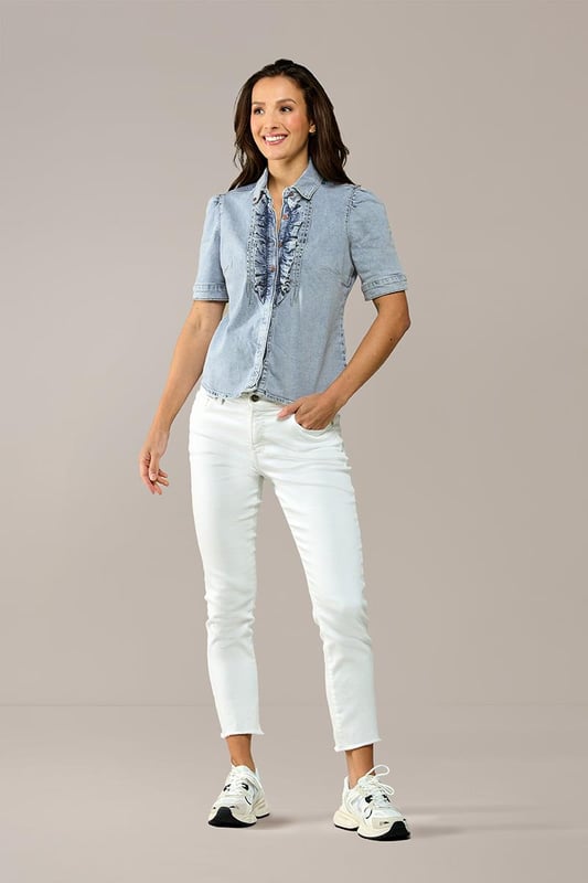 Ga deze zomer voor een trendy blouse met een denim look! Dit prachtige item uit mijn nieuwste collectie is een echte must-have voor een stijlvolle uitstraling. De blouse, uitgevoerd in een zachte lichtblauwe tint, heeft korte pofmouwen en een elegante opstaande kraag. De knoopsluiting is voorzien van speelse ruches, wat een subtiel vrouwelijke touch toevoegt. De getailleerde pasvorm en heuplengte flatteren je figuur op een natuurlijke manier. Gemaakt van biologisch katoen biedt deze blouse niet alleen stijl, maar ook ultiem comfort. Het stretchdenim vormt zich mooi naar je lichaam en benadrukt je vrouwelijke vormen. Verkrijgbaar in meerdere kleuren, zoals wit en mediumblauw.