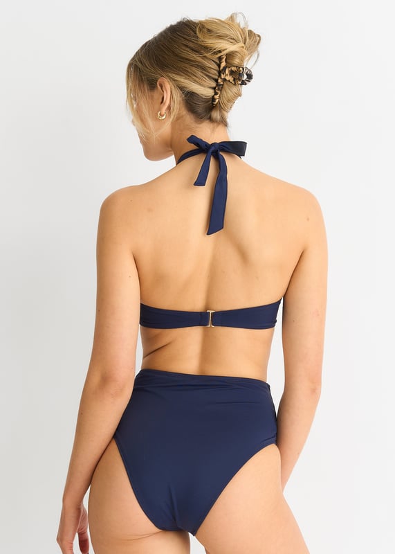 Indulge in luxury with our Navy Twist Front Halter Neck Bikini Top. The elegant twist detail and halter neck design exude sophistication and style. Made with high-quality materials, it offers comfort and support while flattering your figure. Perfect for a day by the pool or a tropical getaway.