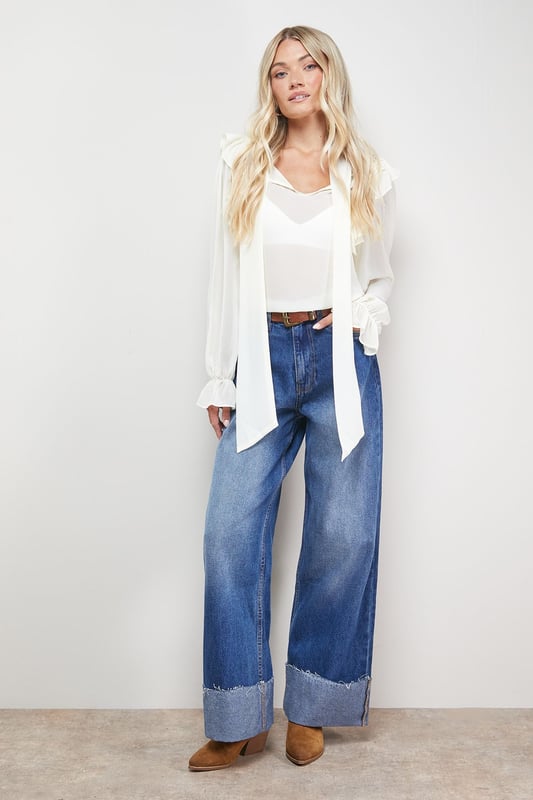 Distinctive turnup hem detail creates a contemporary silhouette
        Straight leg design offers a relaxed, comfortable fit
        High-rise waistband for a flattering shape
        Classic five-pocket styling with traditional stitching
        Wide leg opening with substantial cuff detail for a fashion-forward look
    
    These Oasis denim straight leg jeans combine timeless style with modern detailing. The relaxed fit and statement turnup hem create a fresh, contemporary look that's perfect for everyday wear. Style with a simple white tee and tan accessories for an effortlessly chic daytime ensemble, or pair with a floral blouse and ballet flats for weekend brunches and casual gatherings. The versatile straight leg silhouette works beautifully with both fitted and oversized tops, making these jeans a true wardrobe staple. For cooler days, layer with an oversized cardigan or denim jacket and trainers for a casual yet put-together look. The high-rise waist and relaxed fit through the leg ensure all-day comfort without compromising on style.