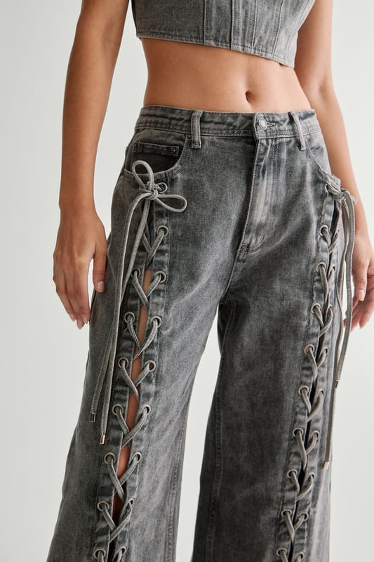 Striking lace-up detail along the sides
        High-waisted design for a flattering silhouette
        Wide-leg cut for a trendy, relaxed look
        Cropped top with square neckline and thick straps
        Back lace-up closure on the top for adjustable fit
    
    Make a bold statement with these eye-catching jeans from NastyGal. The standout lace-up detail running along the sides adds a daring edge to your casual ensemble. Pair with the matching cropped top for a coordinated look that's sure to turn heads. The high-waisted, wide-leg cut is perfect for creating a long, lean silhouette. Style with chunky trainers for a laid-back vibe, or dress up with heeled boots for evening drinks. These versatile jeans are ideal for family gatherings, brunches with friends, or casual Friday at the office. The denim fabric offers comfort and durability, making these jeans a wardrobe staple you'll reach for time and time again.