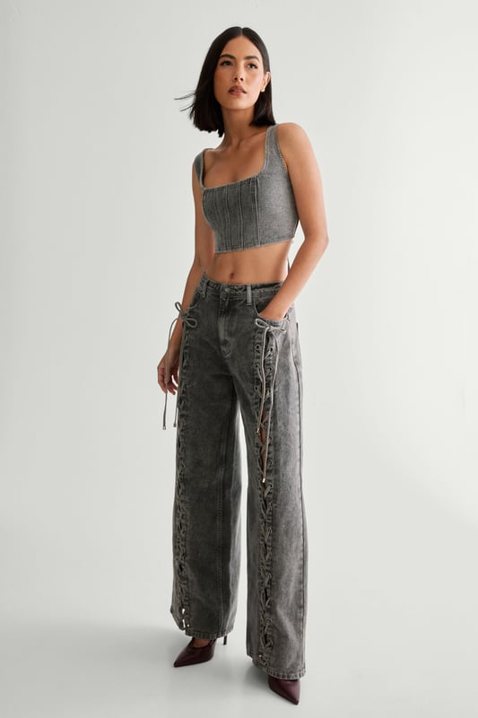 Striking lace-up detail along the sides
        High-waisted design for a flattering silhouette
        Wide-leg cut for a trendy, relaxed look
        Cropped top with square neckline and thick straps
        Back lace-up closure on the top for adjustable fit
    
    Make a bold statement with these eye-catching jeans from NastyGal. The standout lace-up detail running along the sides adds a daring edge to your casual ensemble. Pair with the matching cropped top for a coordinated look that's sure to turn heads. The high-waisted, wide-leg cut is perfect for creating a long, lean silhouette. Style with chunky trainers for a laid-back vibe, or dress up with heeled boots for evening drinks. These versatile jeans are ideal for family gatherings, brunches with friends, or casual Friday at the office. The denim fabric offers comfort and durability, making these jeans a wardrobe staple you'll reach for time and time again.