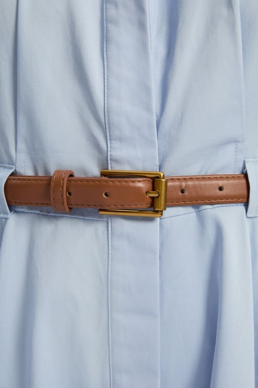 This Karen Millen collared midi dress combines timeless sophistication with practical daywear comfort. The structured silhouette features thoughtful pleating that creates a flattering A-line shape, whilst the included belt cinches the waist for a customised fit. Style with flat sandals and a woven tote for weekend brunches, or dress it up with ballet flats and a cardigan for family gatherings. The cotton fabric ensures this piece remains a comfortable choice for all-day wear, making it an essential addition to your casual-stylish wardrobe.  Crafted from pure cotton for breathable comfort Tailored silhouette with structured collar and cap sleeves Matching belt with gold-tone buckle Full midi skirt with pleating detail Button-through front design