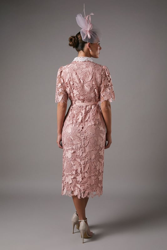 Exquisite lace overlay with intricate floral pattern
        Contrasting white collar for a striking visual effect
        Elegant midi length with a sophisticated side slit
        Short puff sleeves with delicate scalloped edges
        Button-down front for a classic shirt dress silhouette
    
    This stunning lace shirt dress from Coast is the epitome of refined elegance. The intricate floral lace overlay creates a captivating visual texture, while the contrasting white collar adds a touch of sophistication. Perfect for formal occasions, this dress can be styled with strappy heels and statement earrings for a wedding or the races. The midi length and side slit offer a flattering silhouette, allowing for graceful movement. For a more versatile look, pair it with pointed-toe court shoes and a clutch bag for an evening soire. The button-down front and collared neckline give a nod to classic tailoring, making this dress a timeless addition to your occasion wear collection. Whether you're attending a graduation ceremony or a garden party, this Coast dress will ensure you stand out with its blend of traditional charm and contemporary allure.
