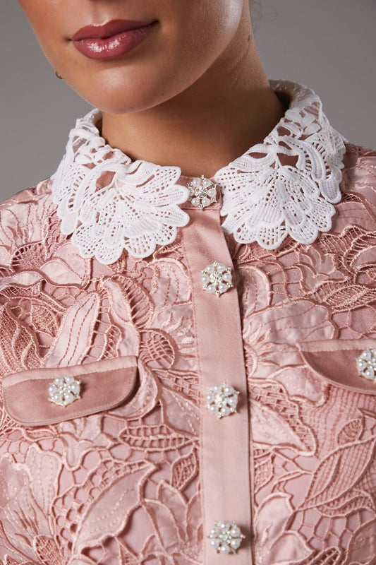 Exquisite lace overlay with intricate floral pattern
        Contrasting white collar for a striking visual effect
        Elegant midi length with a sophisticated side slit
        Short puff sleeves with delicate scalloped edges
        Button-down front for a classic shirt dress silhouette
    
    This stunning lace shirt dress from Coast is the epitome of refined elegance. The intricate floral lace overlay creates a captivating visual texture, while the contrasting white collar adds a touch of sophistication. Perfect for formal occasions, this dress can be styled with strappy heels and statement earrings for a wedding or the races. The midi length and side slit offer a flattering silhouette, allowing for graceful movement. For a more versatile look, pair it with pointed-toe court shoes and a clutch bag for an evening soire. The button-down front and collared neckline give a nod to classic tailoring, making this dress a timeless addition to your occasion wear collection. Whether you're attending a graduation ceremony or a garden party, this Coast dress will ensure you stand out with its blend of traditional charm and contemporary allure.