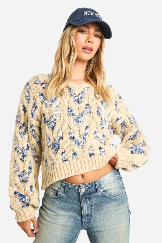 Striking cable knit pattern with floral motif
        Cropped length for a trendy silhouette
        V-neckline adds a feminine touch
        Voluminous balloon sleeves for dramatic flair
        Ribbed cuffs and hem for a snug fit
    
    This eye-catching Zopfmuster-Pullover from Boohoo is the perfect blend of cosy comfort and contemporary style. The intricate cable knit pattern adorned with a delicate floral motif creates a visually stunning texture that's sure to turn heads. Its cropped length and V-neckline offer a flattering silhouette, while the voluminous balloon sleeves add a touch of drama to your ensemble. Ideal for casual outings, this jumper pairs beautifully with high-waisted jeans and trainers for a laid-back look. Layer it under a long coat and accessorise with a baseball cap for an effortlessly cool vibe. Whether you're meeting friends for coffee or heading to a family gathering, this versatile piece will keep you looking stylish and feeling snug.
