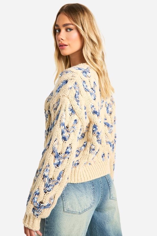 Striking cable knit pattern with floral motif
        Cropped length for a trendy silhouette
        V-neckline adds a feminine touch
        Voluminous balloon sleeves for dramatic flair
        Ribbed cuffs and hem for a snug fit
    
    This eye-catching Zopfmuster-Pullover from Boohoo is the perfect blend of cosy comfort and contemporary style. The intricate cable knit pattern adorned with a delicate floral motif creates a visually stunning texture that's sure to turn heads. Its cropped length and V-neckline offer a flattering silhouette, while the voluminous balloon sleeves add a touch of drama to your ensemble. Ideal for casual outings, this jumper pairs beautifully with high-waisted jeans and trainers for a laid-back look. Layer it under a long coat and accessorise with a baseball cap for an effortlessly cool vibe. Whether you're meeting friends for coffee or heading to a family gathering, this versatile piece will keep you looking stylish and feeling snug.