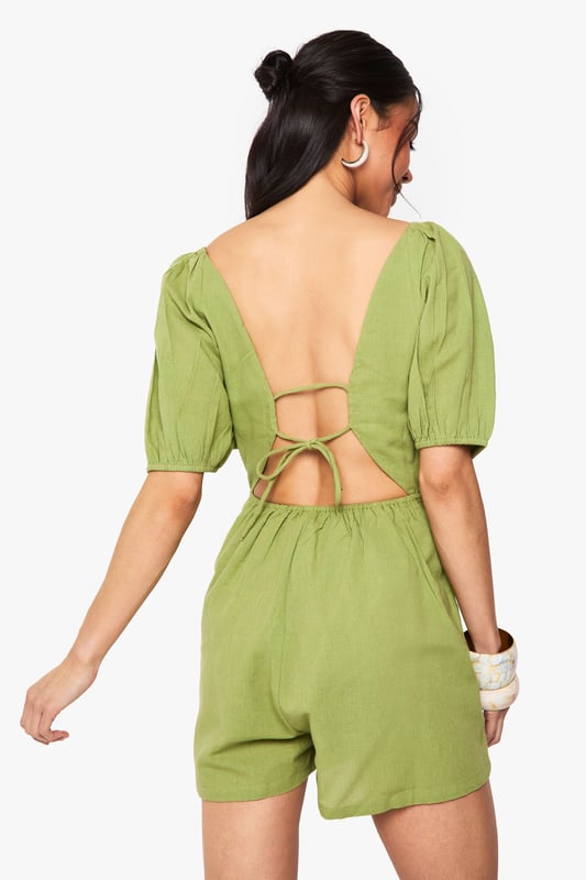 Crafted from a breathable linen mix fabric, perfect for warm-weather occasions
        Featuring charming puff sleeves for a feminine, on-trend silhouette
        Flattering V-neckline frames the dcolletage beautifully
        Striking open back design with delicate tie detail for added interest
        Relaxed fit shorts provide comfort whilst maintaining a stylish appearance
    
    This delightful linen mix playsuit combines comfort with effortless style for your casual wardrobe. The feminine puff sleeves create a romantic silhouette, while the plunging V-neckline adds a touch of allure. The standout feature is undoubtedly the open back with tie detailing, creating visual interest when you turn around. Style with flat sandals and a woven bag, as shown on our model, for daytime gatherings or family brunches. For a more polished look, add statement earrings and metallic accessories. The versatile design works brilliantly for garden parties, seaside holidays or casual weekend outings. The breathable fabric ensures you'll stay comfortable throughout the day, making this playsuit a summer wardrobe essential that delivers both practicality and style in equal measure.