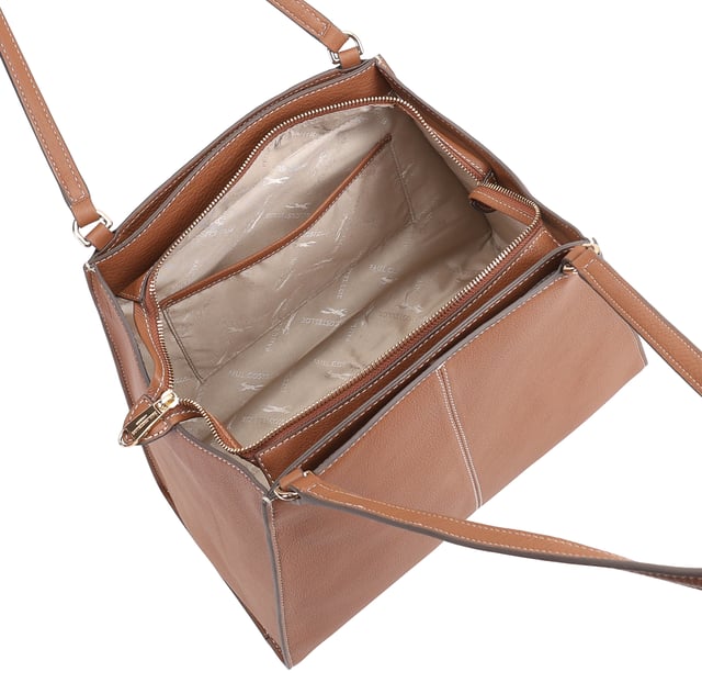 This uniquely shaped leather tote bag combines elegance with practicality, featuring a spacious central compartment secured by a top zip, perfect for work or casual outings. It offers convenient organization with external slip pockets on both sides, an internal zip pocket, and an additional slip pocket inside. Designed for comfort, the long shoulder handles make it easy to carry all day, while the clean silhouette is elevated by a sleek metal logo pin for a touch of refined style. D:18cm W:42.5cm H:27.5