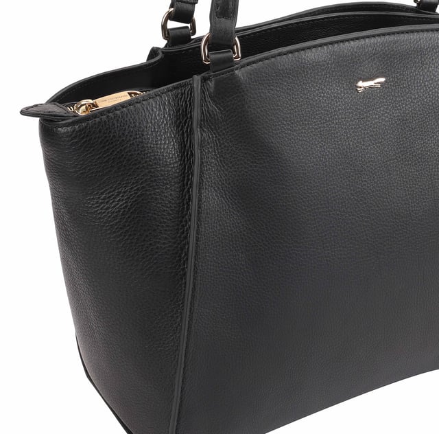 This uniquely shaped leather tote bag combines elegance with practicality, featuring a spacious central compartment secured by a top zip, perfect for work or casual outings. It offers convenient organization with external slip pockets on both sides, an internal zip pocket, and an additional slip pocket inside. Designed for comfort, the long shoulder handles make it easy to carry all day, while the clean silhouette is elevated by a sleek metal logo pin for a touch of refined style. D:18cm W:42.5cm H:27.5