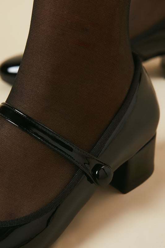 Good For The Sole: Vianne Patent Mary Jane Round Toe Low Heel Pumps Patent Mary Jane style with elegant round toe design
Comfortable low block heel measuring between 0-2cm for all-day wear
Secure strap fastening with decorative button detail
Faux leather finish offering a sophisticated sheen
Part of the Good For the Sole collection designed for comfort and style
The Vianne Mary Jane pumps blend timeless charm with modern practicality, perfect for the professional who refuses to compromise on style or comfort. The classic round toe silhouette paired with the traditional Mary Jane strap creates a refined look that transitions seamlessly from office to evening engagements. Style these versatile flats with tailored trousers and a crisp blouse for a polished workwear ensemble, or pair with a pencil skirt and lightweight cardigan for important meetings. The subtle block heel provides just enough elevation whilst ensuring stability throughout your busy day. These pumps work brilliantly with cropped trousers to showcase their distinctive shape, as seen in the styling. Their understated elegance makes them an essential addition to your workwear rotation, offering the perfect balance of professional refinement and all-day wearability.