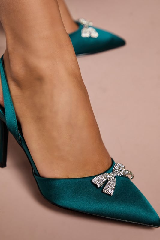 Elegant satin slingback court shoes featuring a stunning diamante bow brooch detail
        Pointed toe silhouette creates a flattering, elongated look
        Sophisticated 8cm stiletto heel adds height whilst maintaining comfort
        Wide fit design offers additional room for all-day wear
        Secure slingback strap with elasticated insert ensures the perfect fit
    
    The Scarlett slingback heels from Coast are the epitome of occasion-worthy footwear. These striking court shoes combine timeless elegance with contemporary flair, featuring a luxurious satin finish and eye-catching diamante bow brooch that catches the light beautifully with every step. The pointed toe and sleek stiletto heel create a refined silhouette that complements both midi and full-length gowns perfectly. Style with a tailored dress for a wedding or pair with a structured jumpsuit for the races. The wide fit construction ensures comfort throughout formal events, whilst the slingback design adds a touch of vintage charm. These versatile heels transition effortlessly from daytime ceremonies to evening receptions, making them a worthy investment for your special occasion wardrobe.