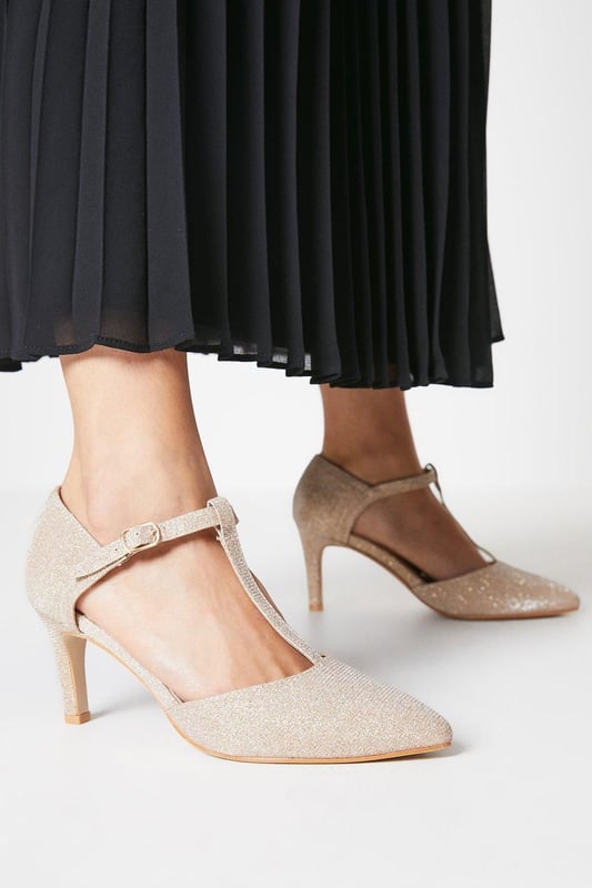 Elegant T-bar design with adjustable ankle strap for secure fit
        Pointed toe silhouette creates a flattering, elongated look
        Extra wide fit specially designed for enhanced comfort
        High heel measuring between 7-9cm adds sophisticated height
        Faux leather finish offers a polished, versatile appearance
    
    The Emma court shoes from Good For The Sole combine timeless style with exceptional comfort. Designed specifically with an extra wide fit, these pointed courts feature a classic T-bar strap that adds a touch of vintage charm while providing additional support. The high heel creates an elegant silhouette without compromising on wearability, making these courts perfect for daytime events where you want to make an impression. Style them with tailored trousers and a crisp blouse for family gatherings, or pair with a flowing midi skirt for casual lunches with friends. The neutral tone makes these courts incredibly versatile, allowing them to complement virtually any outfit in your wardrobe. The secure ankle strap ensures stability while the pointed toe design conveys sophistication, striking the perfect balance between fashion and function.